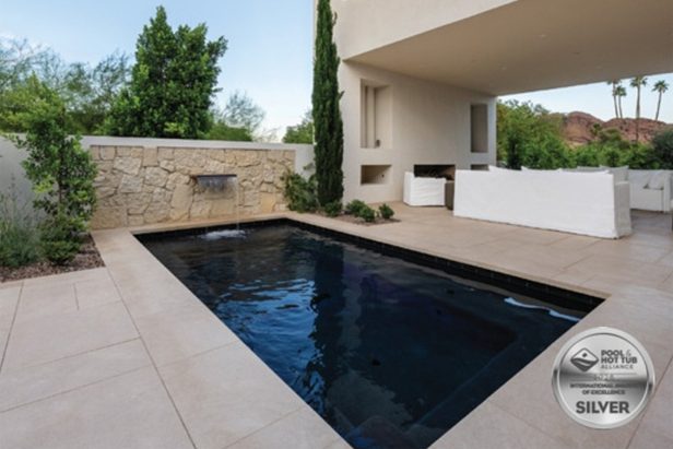 The 2026 PHTA Silver-winning geometric pool by Morris Pools: dark rectangular pool with a stacked-stone water wall and covered patio, as published in AQUA Magazine
