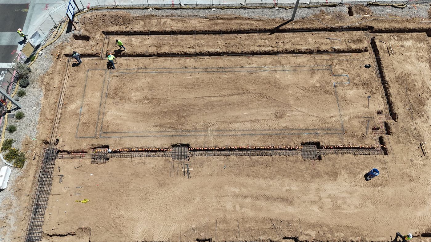 Aerial view of an early pool layout marked out in the dirt, with steel reinforcement laid along the trenches