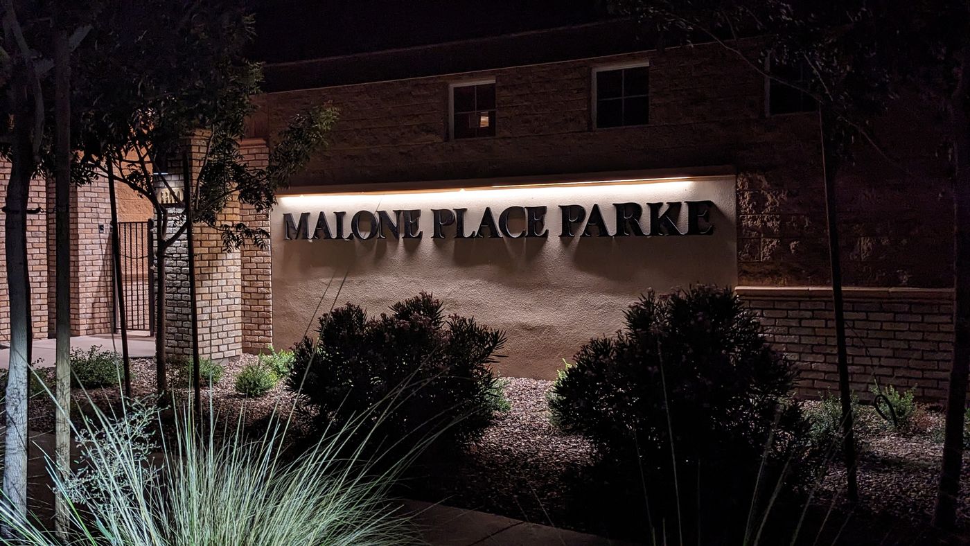 Malone Place Parke community sign lit at night, set in a stone wall