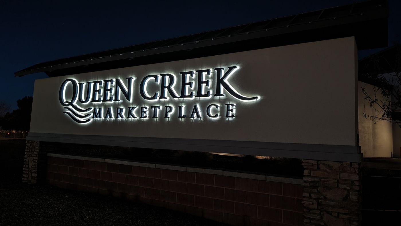 Illuminated Queen Creek Marketplace sign at night