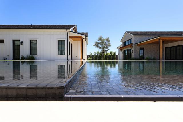 Mirror-still dark pool with a knife edge reflecting a white farmhouse and guest house