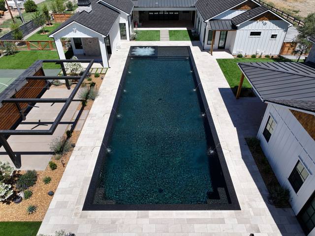 Aerial view of a long rectangular black-finish lap pool in a modern farmhouse courtyard