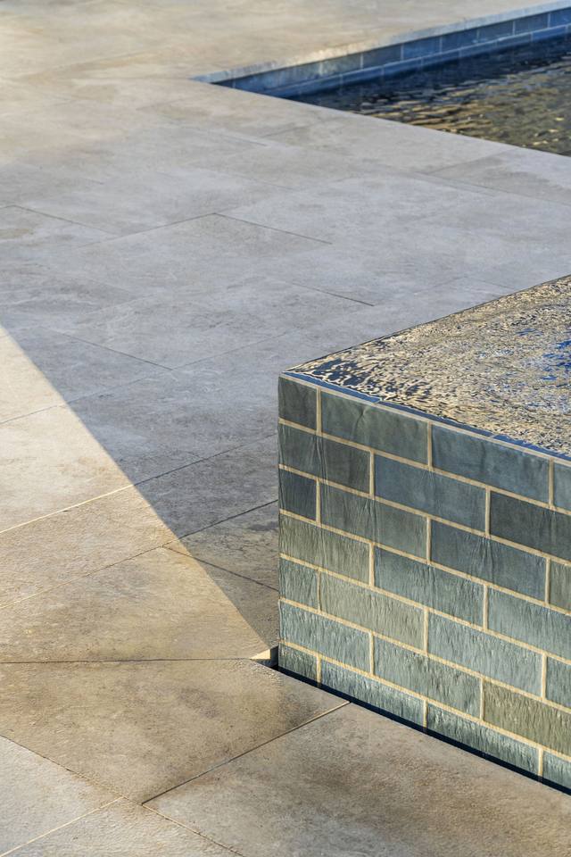 Close-up of a raised spa wall finished in blue-gray glass tile