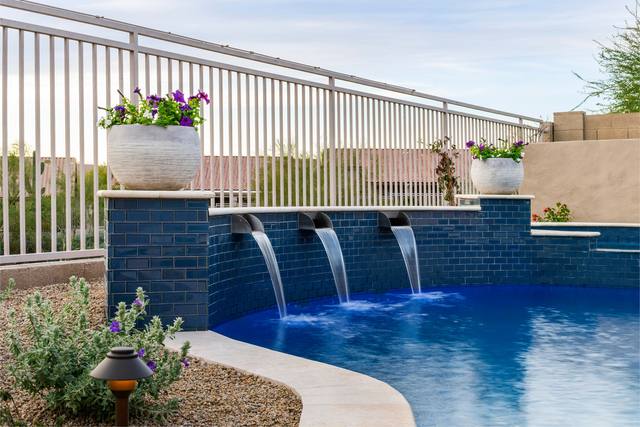 Three sheer descents pouring from a blue-tiled raised wall into a freeform pool