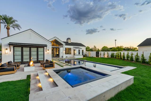 The 2023 PHTA Bronze-winning pool by Morris Pools: rectangular pool with sunken lounge seating and fire features beside a white modern farmhouse