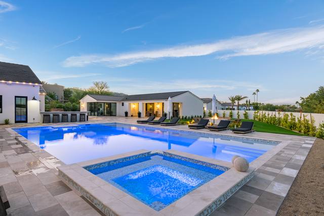 Large rectangular pool with raised spa and gray paver deck at a modern ranch home
