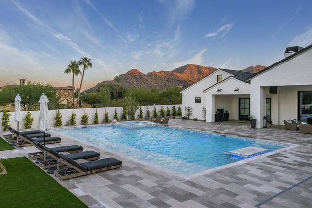 Pool with sun shelf and chaise loungers, desert mountains and palms in the background