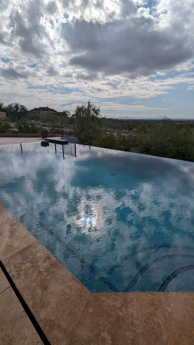Infinity-edge pool reflecting clouds above the desert