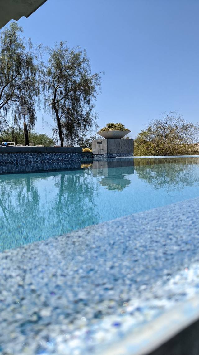 Close-up of a pool edge with pebble finish and a perimeter overflow