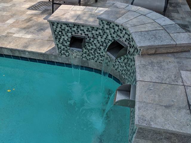 Spa spillway in green glass tile flowing into the pool