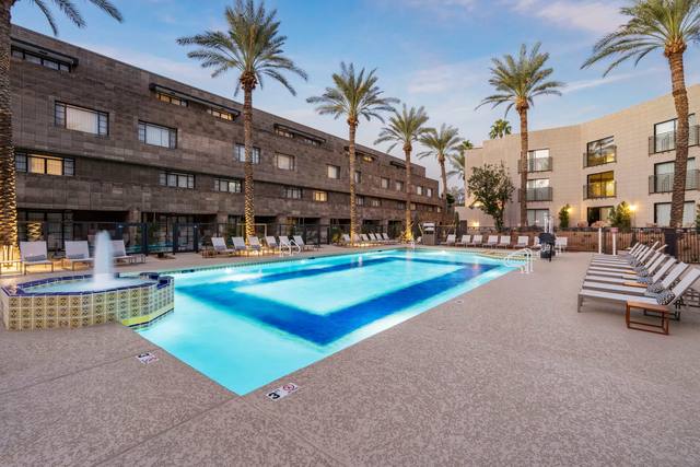 Commercial resort-style hotel pool with fountain spa and palm trees