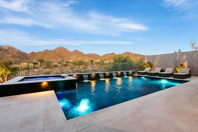 A 2024 PHTA Bronze-winning geometric pool by Morris Pools: rectangular pool and raised spa with sheer descents and a mountain view at dusk