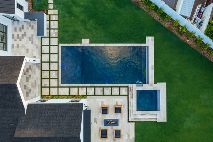 Aerial view of a geometric pool and spa set into lawn and pavers